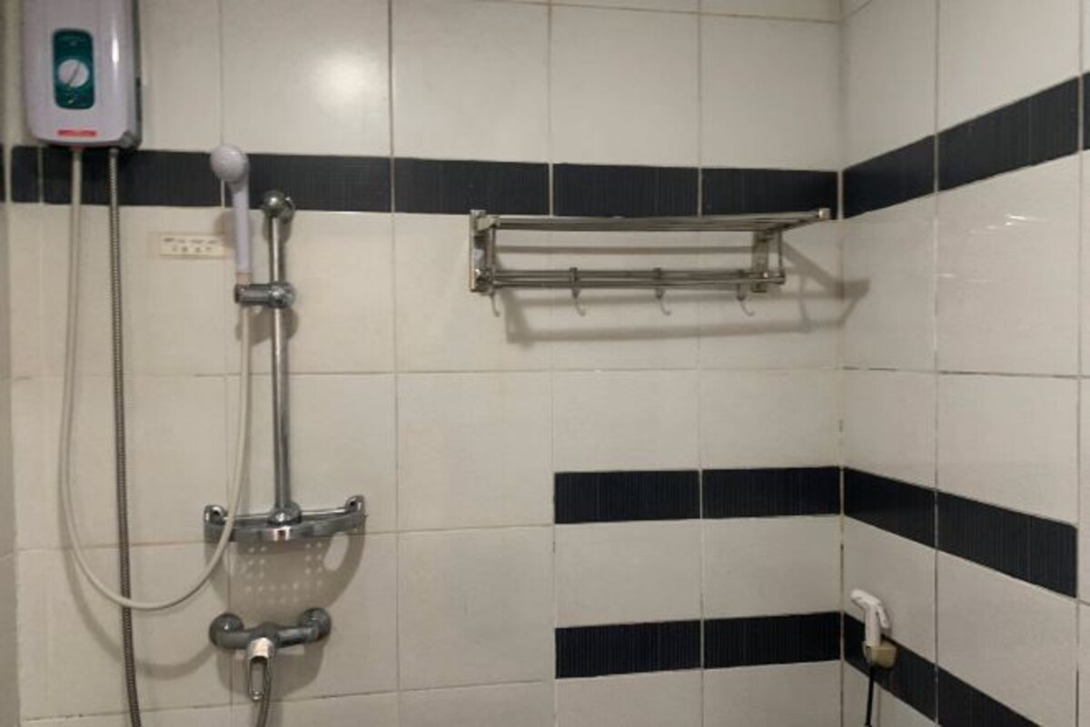 A bathroom with a shower, a towel rack, and a soap dispenser.