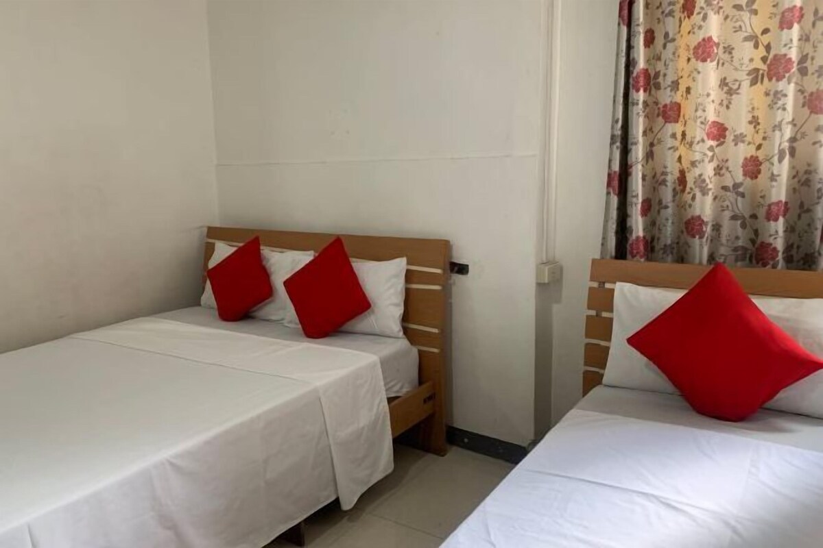 A room with two single beds, each with a wooden headboard and white bedding.