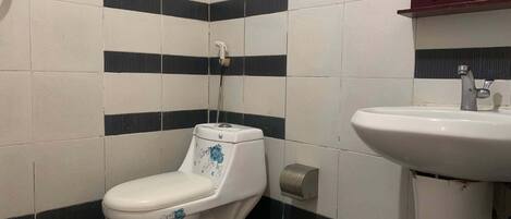 A bathroom with a toilet, a sink, and a mirror.