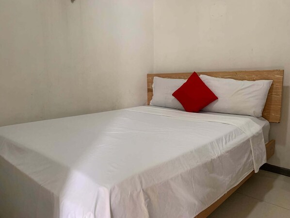 A single-bed room with a wooden headboard, white bedding, and a red accent pillow. - Lucky Hotel Binondo (Manila)