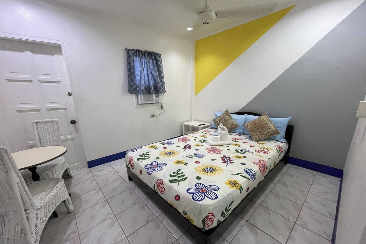 A bedroom with a bed, a small table, and a chair.