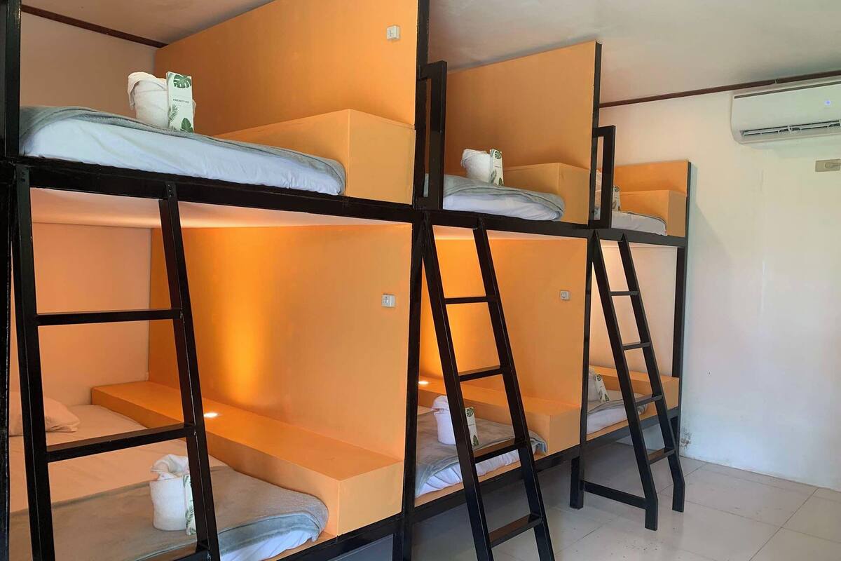 Een slaapkamer met een stapelbed, een witte muur en een airconditioning.