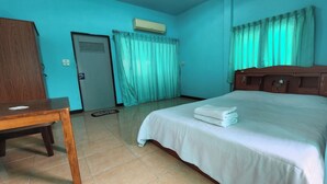 A hotel room with a bed, a wooden desk, a door, and a window with curtains. - Chok Phikul Thong Resort (Kamphaeng Saen)