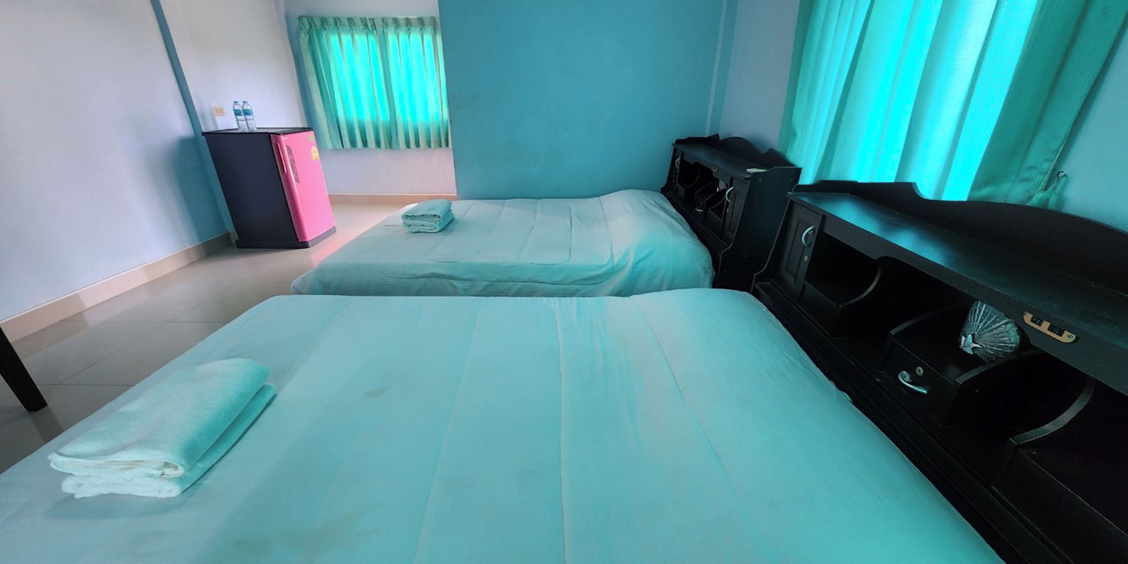 Habitación de hotel con dos camas, un escritorio, un aparador y una ventana con cortinas.