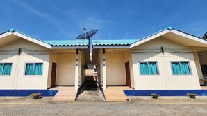 A two-story building with a central entrance, satellite dish, and blue trim. - Chok Phikul Thong Resort (Kamphaeng Saen)