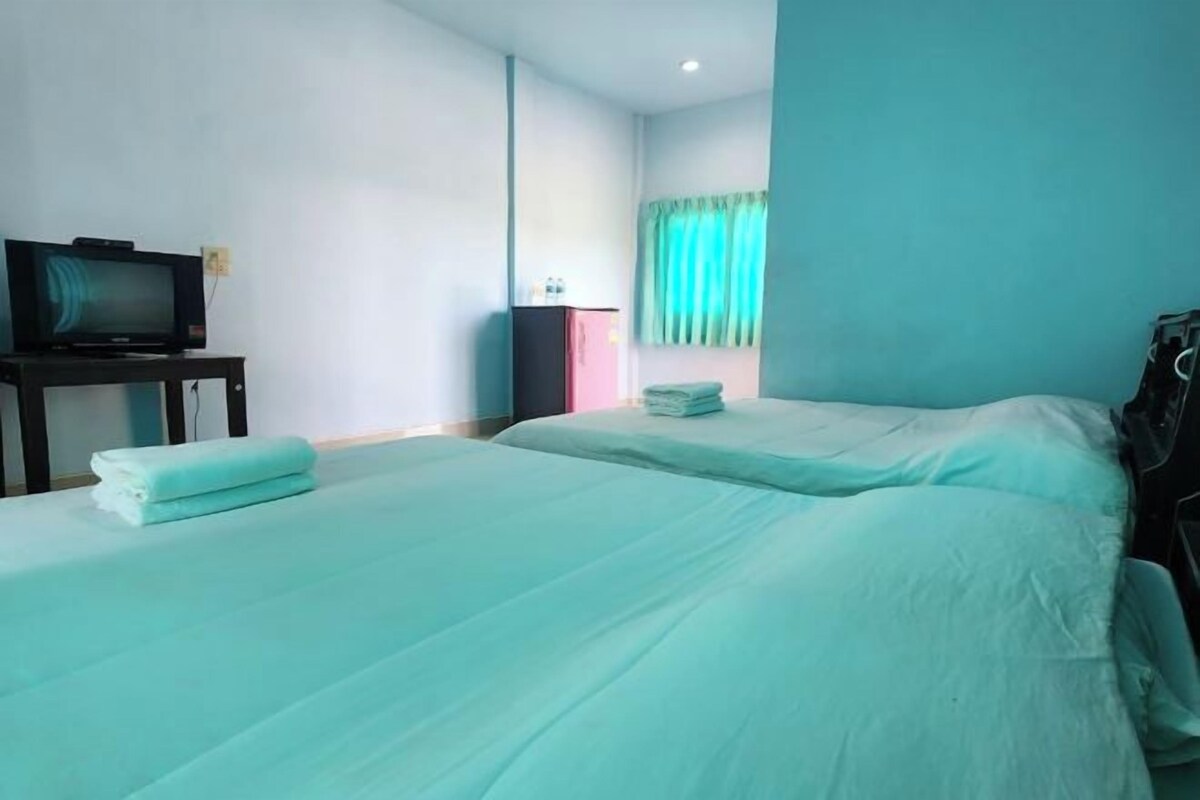 A hotel room with two beds, a television on a stand, and a wardrobe.