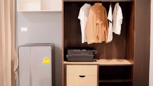 A compact room with a wardrobe, a small desk, and a refrigerator. - Jt Place Buriram (Buriram)