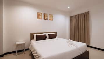 A hotel room with a bed, a bedside table, and a window with curtains.