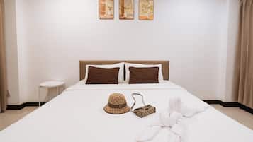 Een hotelkamer met een bed, kussens, een hoed, een handtas en een handdoek.