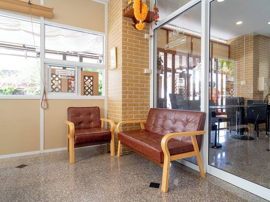 Un hall con dos sofás de cuero, una partición de vidrio y una pared de ladrillo.