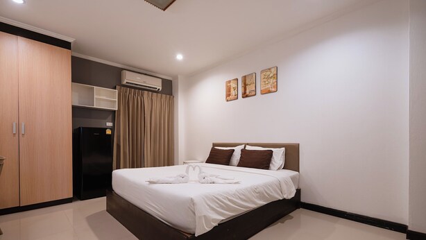A hotel room with a bed, a wardrobe, an air conditioning unit, and a wall-mounted shelf. - Jt Place Buriram (Buriram)