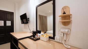 Un baño de hotel con un espejo grande, un lavabo con artículos de aseo, un secador de pelo y un teléfono.