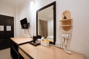 Un baño de hotel con un espejo grande, un lavabo con artículos de aseo, un secador de pelo y un teléfono.