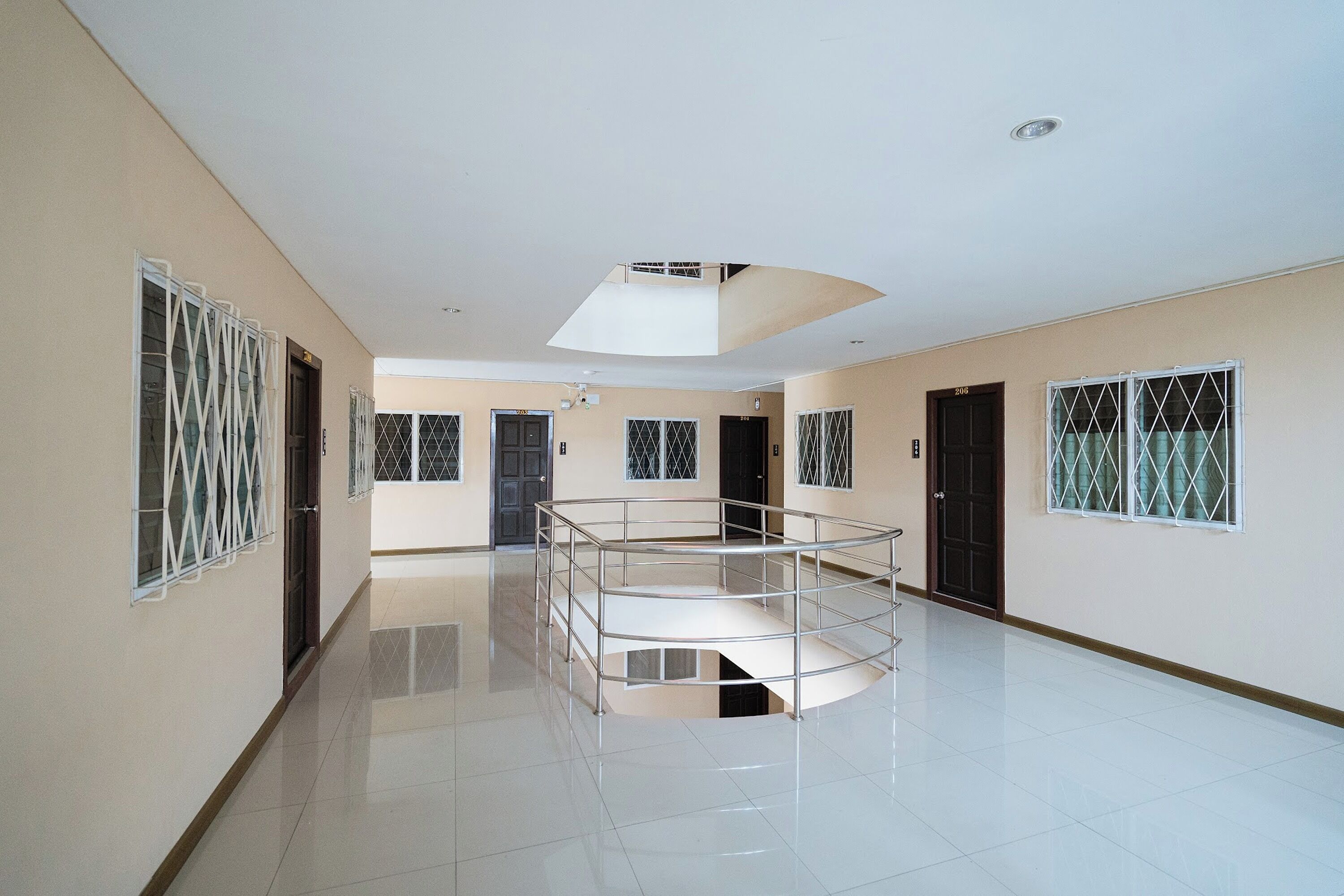 A spacious corridor with a central glass railing, doors numbered 204 and 206, and a ceiling light fixture.