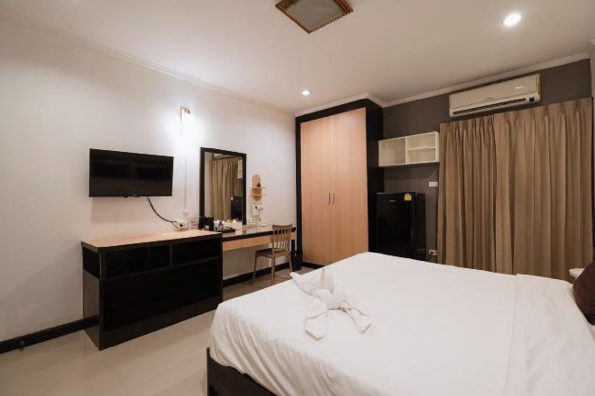 Une chambre d’hôtel équipée d’un lit, d’un bureau avec une chaise, d’une télévision et d’un appareil de climatisation.
