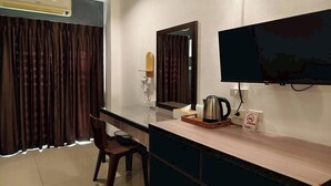 A hotel room with a desk, chair, TV, and a coffee maker. - Jt Place Buriram (Buriram)