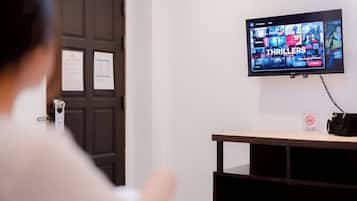 Un televisor mostrando una selección de películas y programas de televisión, fijado en una pared sobre un escritorio con un cartel de 'NO Smoking'.