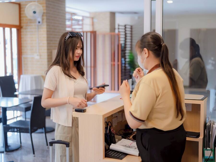 Zona de recepción con mostrador, sillas y un escritorio con computadora y documentos.