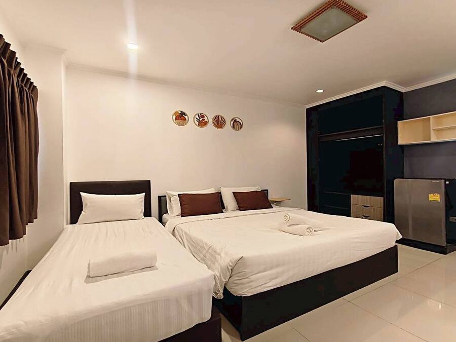 Quarto de hotel com duas camas, um guarda-roupa, um minibar e uma pequena mesa.