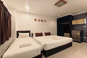 A hotel room with two beds, a wardrobe, a minibar, and a small table. - Jt Place Buriram (Buriram)