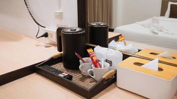 A hotel room with a wooden tray containing a remote control, a white mug, a Nescafé coffee sachet, and a tissue box.