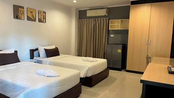 A hotel room with two beds, a desk, a wardrobe, and an air conditioning unit.