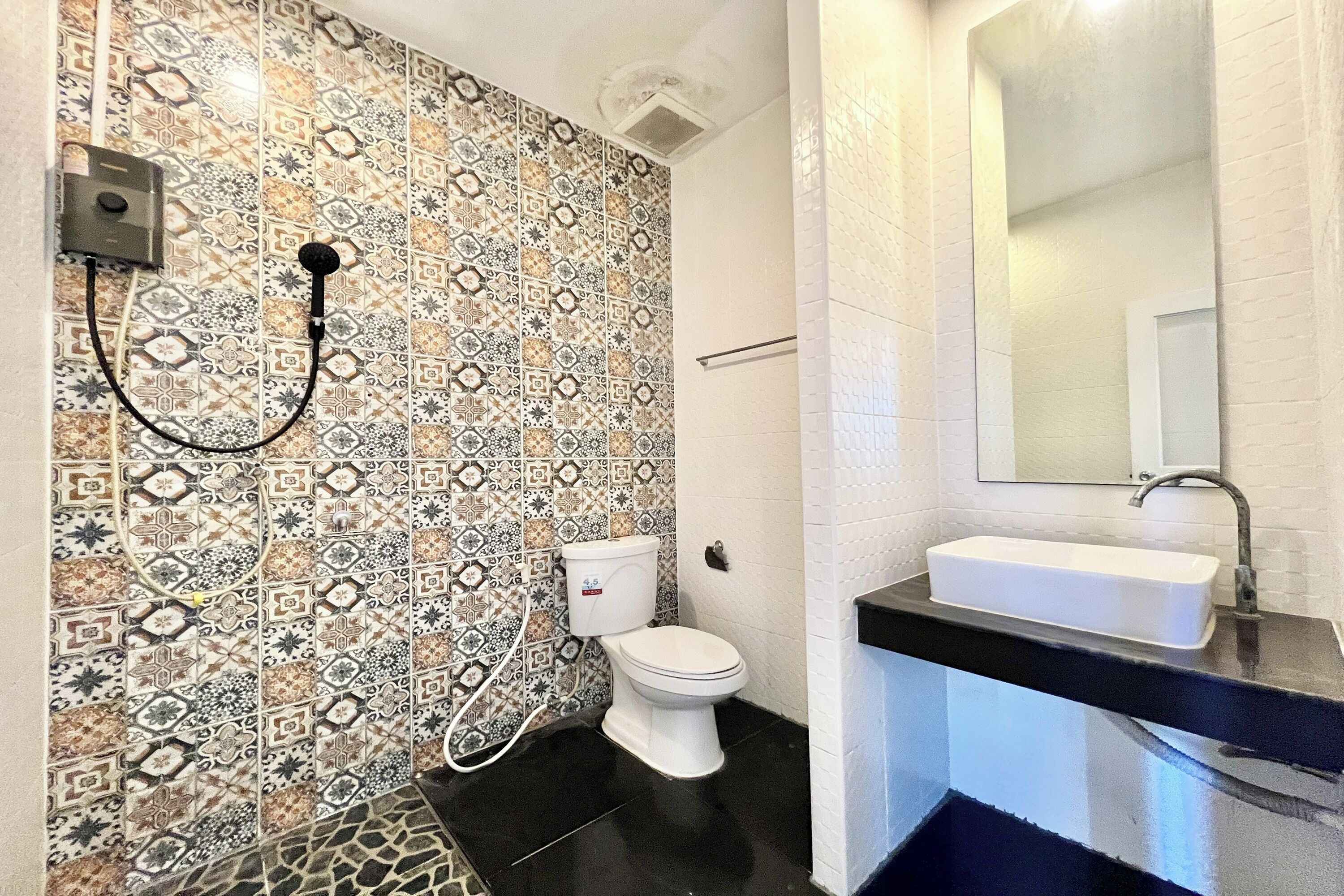 Un bagno con piastrelle decorate, un WC, un lavandino e una doccia.