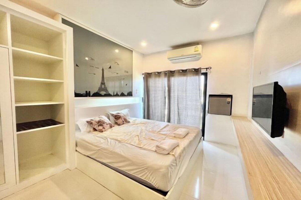Un dormitorio con cama, armario, televisor montado en la pared y aire acondicionado.