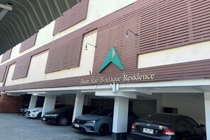 A building with a sign reading "Baan Rao Boutique Residence" and a parking area with several cars. - Baan Rao Boutique Residence (Chiang Mai)