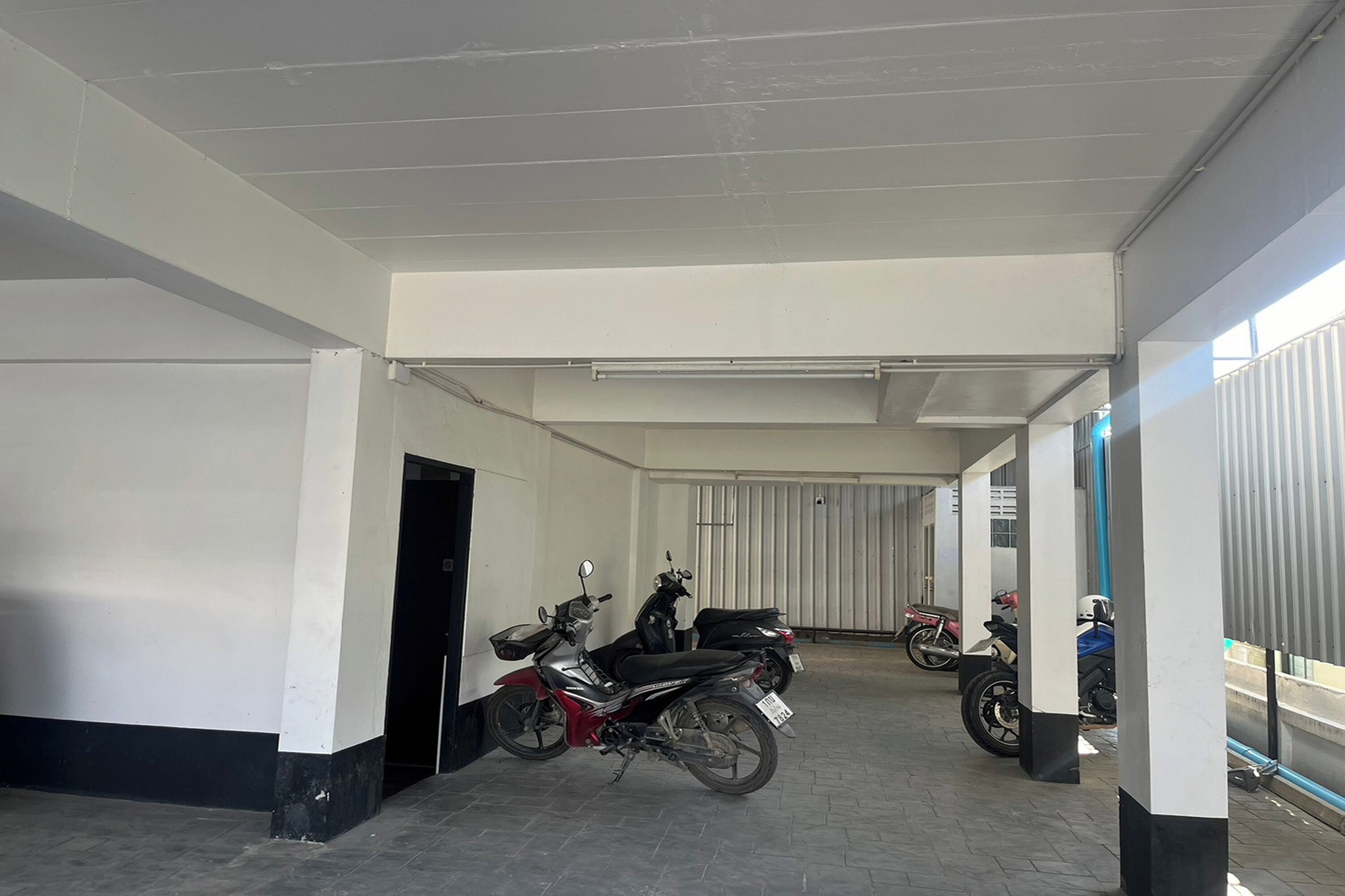 A covered parking area with several motorcycles parked.