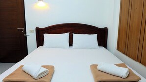 A neatly made bed with white linens and two folded towels on brown bedsheets. - Baan Rao Boutique Residence (Chiang Mai)