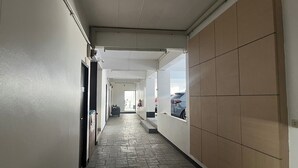 A hallway with tiled flooring, a door on the left, and a wall with a window on the right. - Baan Rao Boutique Residence (Chiang Mai)