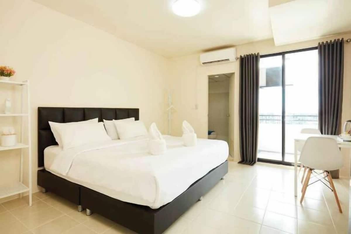Une chambre d’hôtel avec un lit, un bureau, une chaise et un balcon.