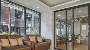 Een modern interieur met een bruine leren bank, een glazen deur naar een eetgedeelte, en een zichtbare keuken met een fontein.