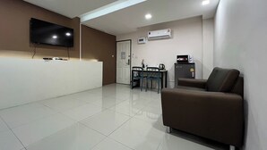 A modern living room with a flat-screen TV, a sofa, a dining table with chairs, and a kitchenette area. - Bansuay Phra Nang Klao Near MRT Phra Nang (Nonthaburi)