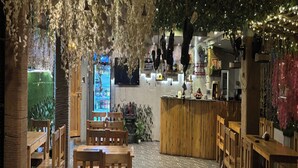 An indoor restaurant with wooden tables and chairs, a counter, and hanging decorations. - Aariv Comforts Baga (Baga)