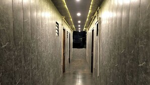 A long, narrow hallway with marble walls and a polished floor, leading to a dark room at the end. - Aariv Comforts Baga (Baga)