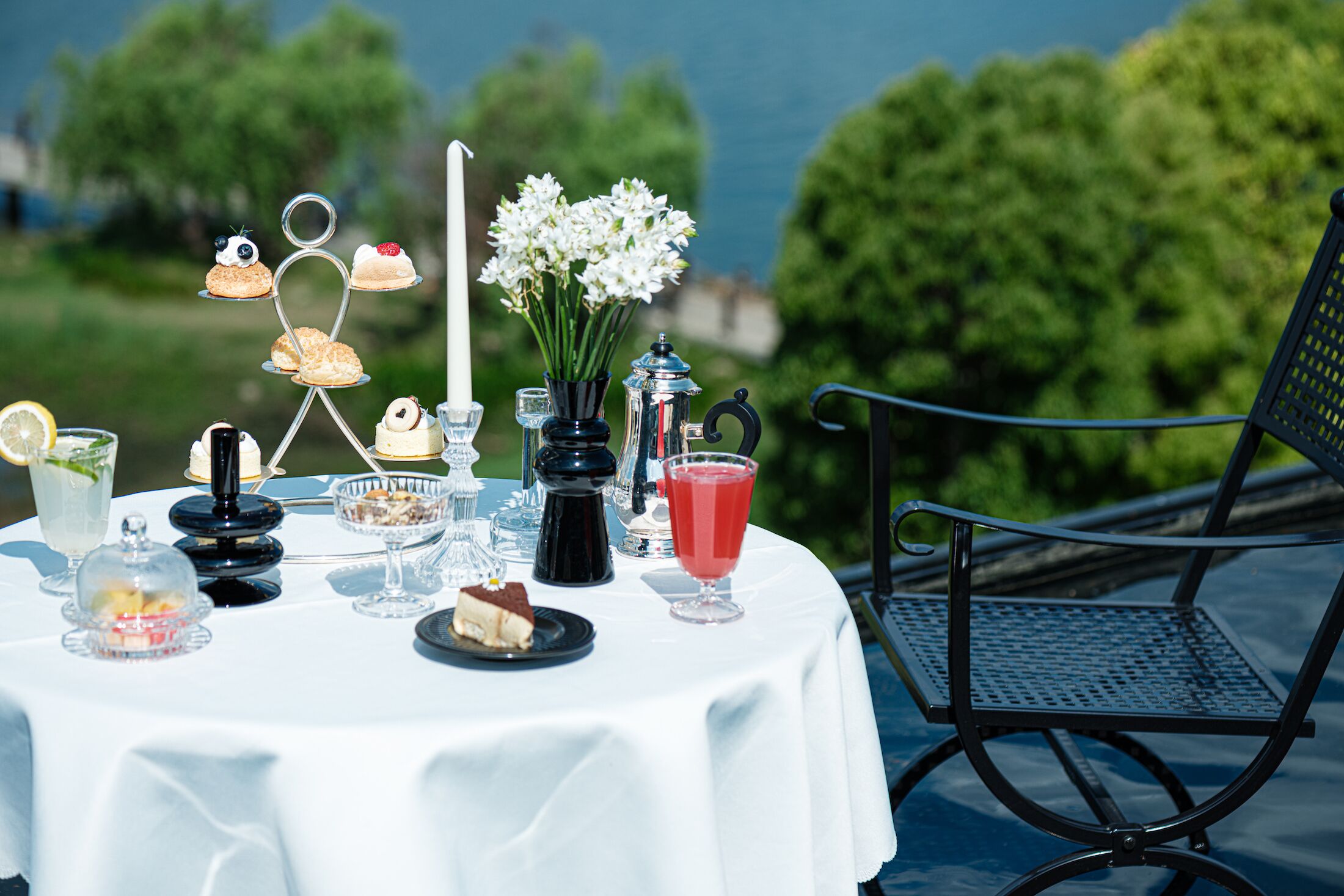 Una mesa al aire libre con diversos postres, bebidas y una vela.