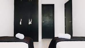 A hotel room with two beds, a large wardrobe, and a door. - Casa con Piscina Privada para Familias (La Aurora)