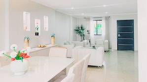 A modern living room with a dining area, featuring a sofa set, a coffee table, and decorative plants. - Casa con Piscina Privada para Familias (La Aurora)