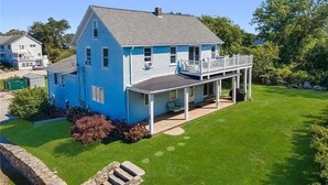 Una casa de dos pisos con fachada azul, un porche cubierto y un césped bien cuidado.