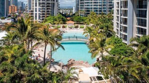 Un resort con piscina central, rodeado de palmeras y edificios modernos.