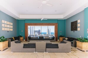 Un amplio salón con un ventanal que ofrece vistas al horizonte de la ciudad y al mar.