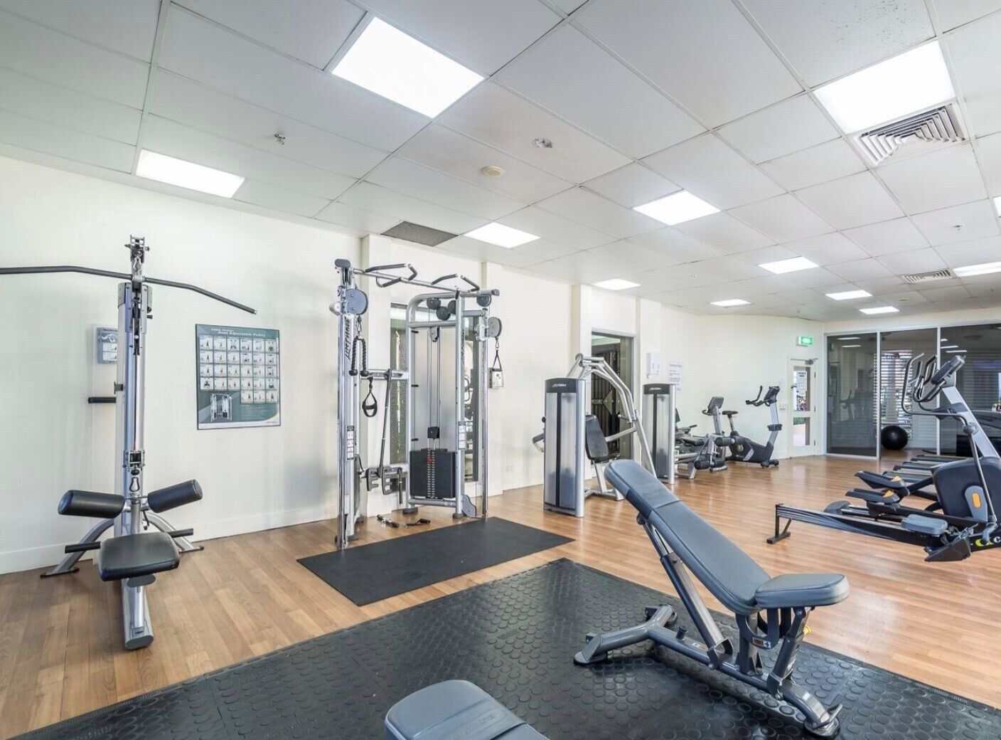 Ein Fitnessstudio mit verschiedenen Trainingsgeräten, darunter Kraftgeräte und Cardiogeräte, sowie einer Spiegelwand.