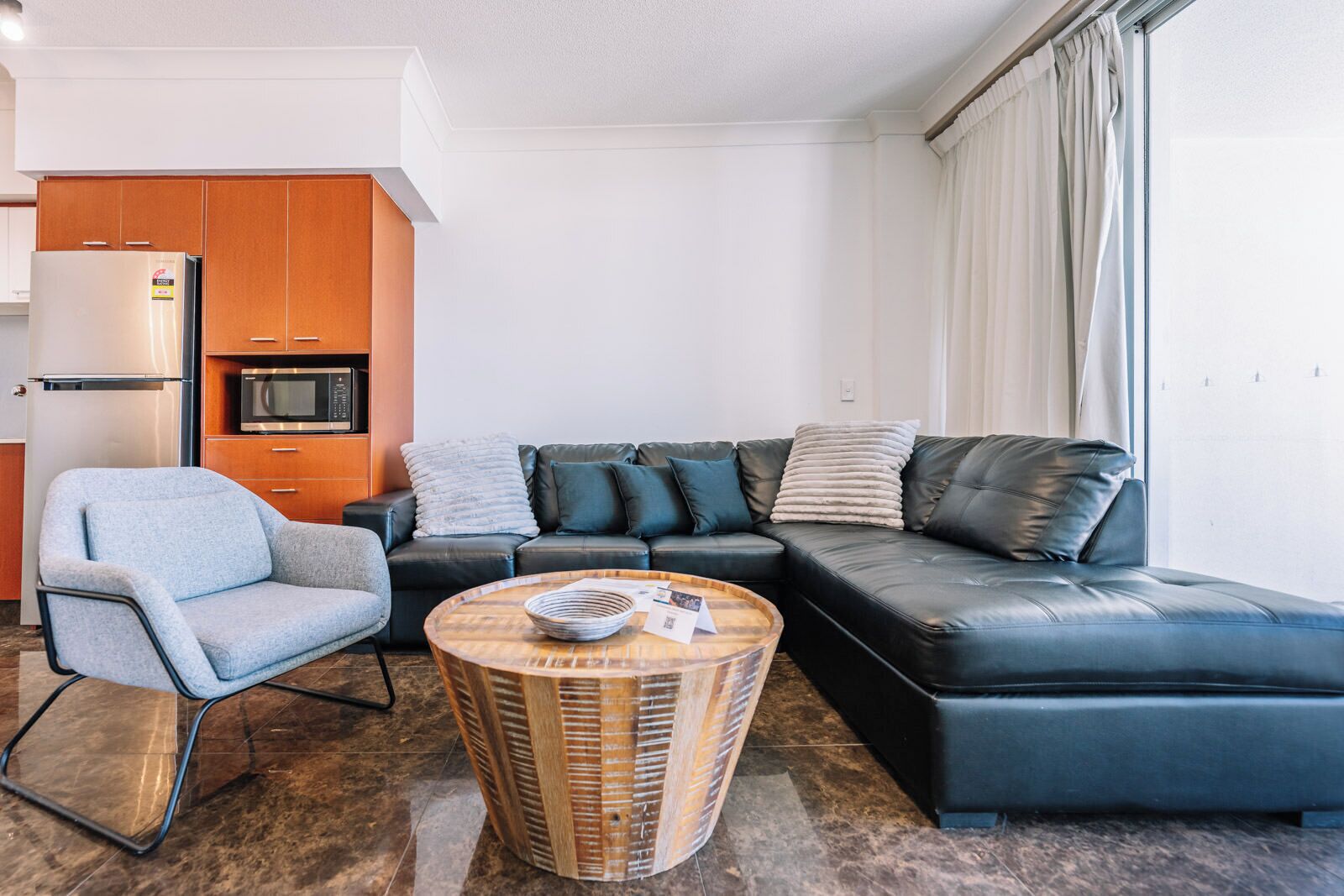 A modern living room with a sectional sofa, a small armchair, and a round coffee table.