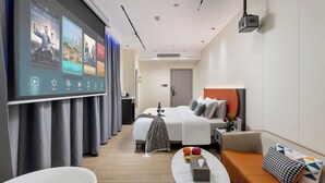 Une chambre d’hôtel moderne équipée d’un lit, d’un canapé, d’une table basse et d’une salle de bain avec baignoire.