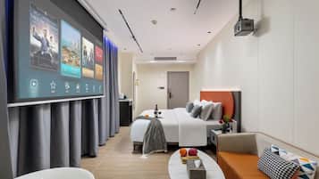 A modern hotel room with a bed, a sofa, a coffee table, and a bathroom with a bathtub.