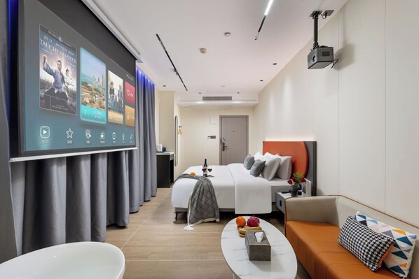 Una habitación de hotel moderna con cama, sofá, mesa de centro y baño con bañera.