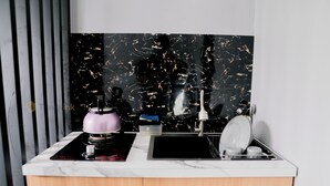 A kitchen with a black marble backsplash, a white countertop, and a wooden cabinet. - Stigma Kubus By Travelink (Kejajar)
