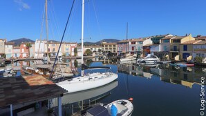 A marina with various boats docked, surrounded by colorful buildings and a clear blue sky.